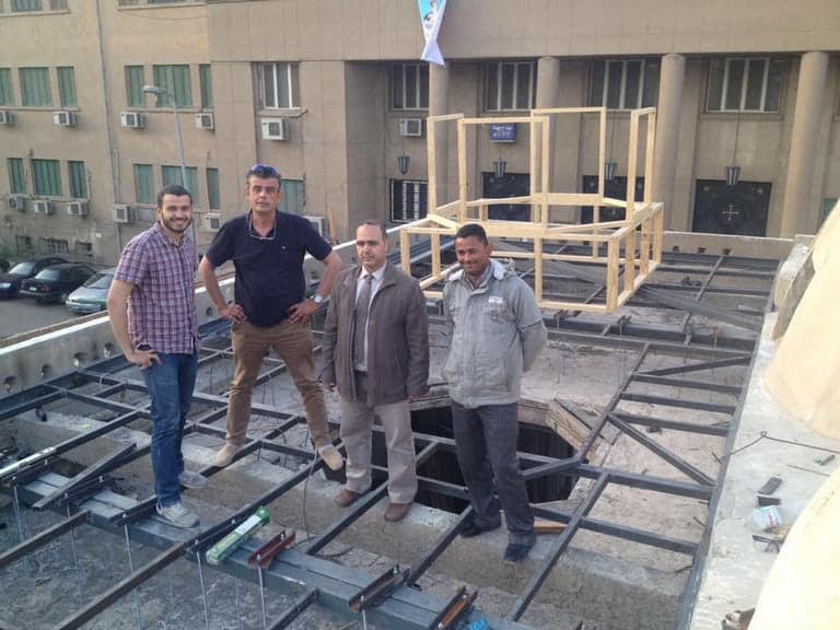 Restoration work in progress at St. Anba Rewis Church, with the steel roof deck exposed and the timber sanctuary frame set out above it